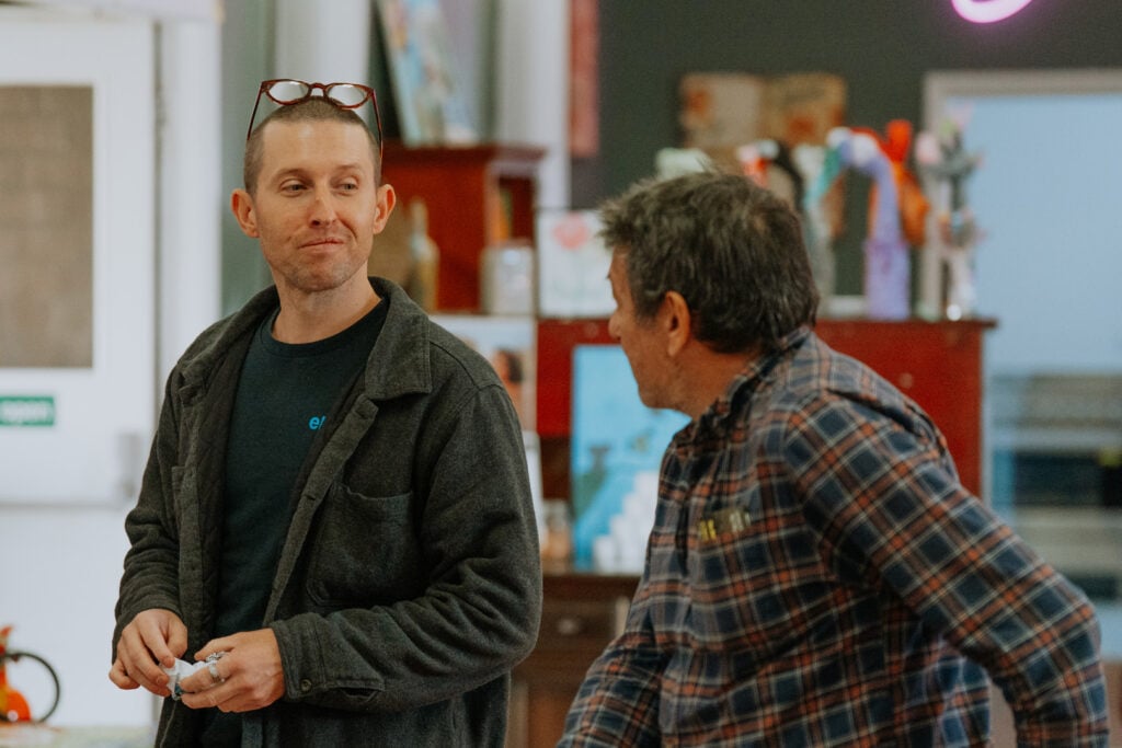 A man with glasses perched on his head is looking off to the side while holding a small item.