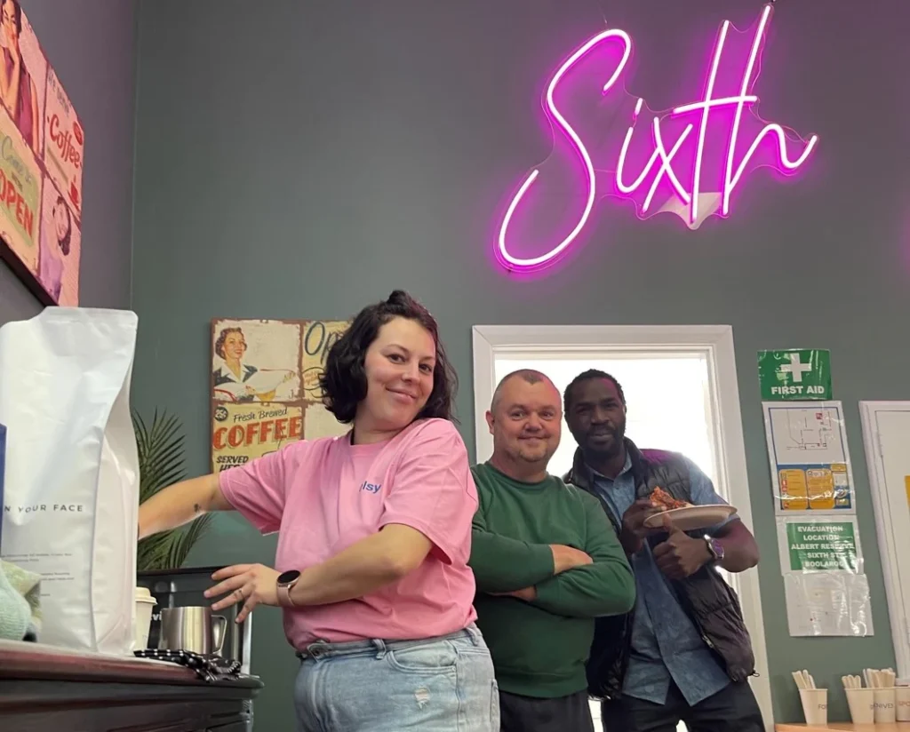 Three people standing inside a café or kitchen area