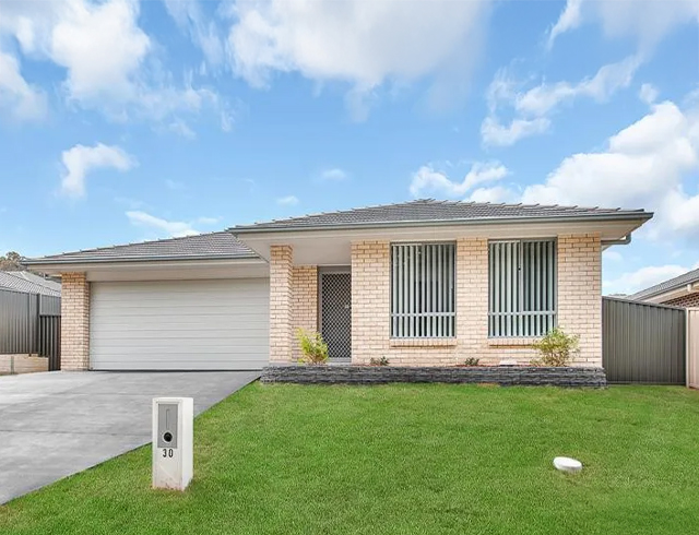 The house has light beige brick walls and a grey tiled roof.